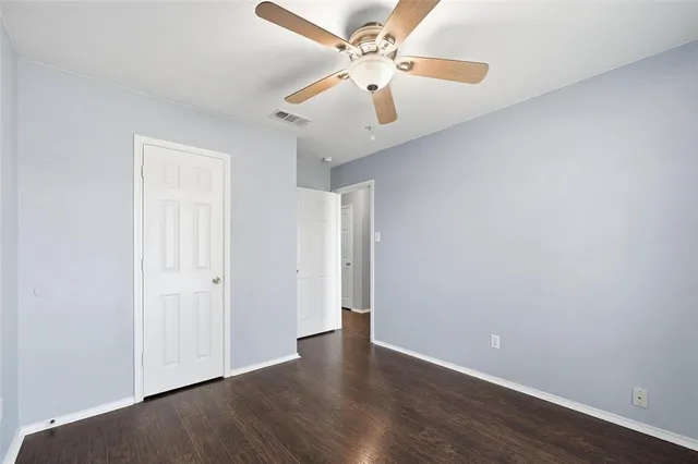 an empty room with wooden floor and ceiling fan