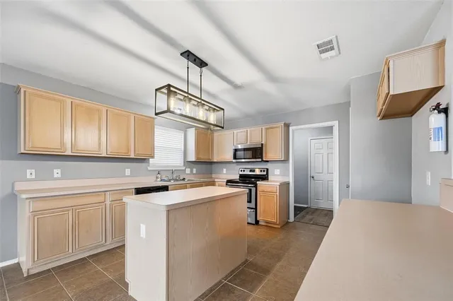 a kitchen with stainless steel appliances a sink stove refrigerator and cabinets