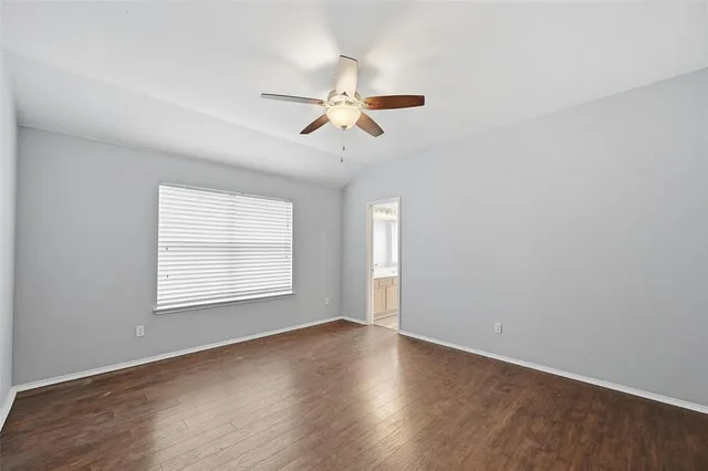 an empty room with wooden floor chandelier fan and windows