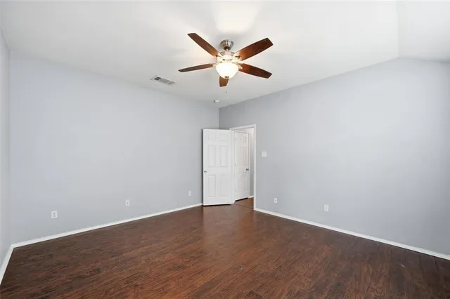 an empty room with wooden floor and ceiling fan