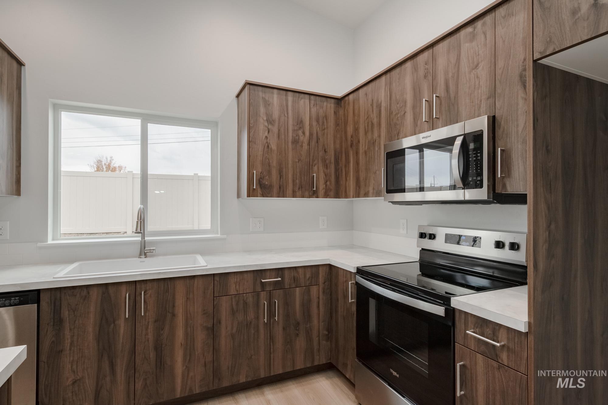 13736 Nisene Street Caldwell, ID 83607 - Photo 6 of 22 Kitchen with appliances with stainless steel finishes, light countertops, modern cabinets, and light wood finished floors