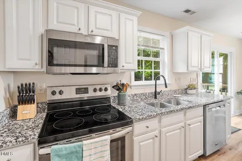 a kitchen with granite countertop white cabinets and window