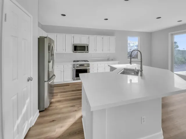 a kitchen with stainless steel appliances granite countertop a sink a stove and a refrigerator