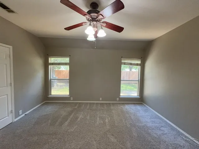 an empty room with windows and fan