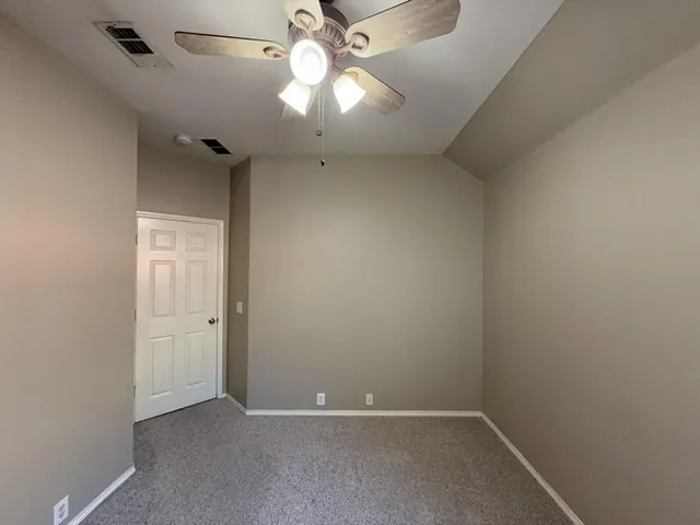 an empty room with a fan & a window
