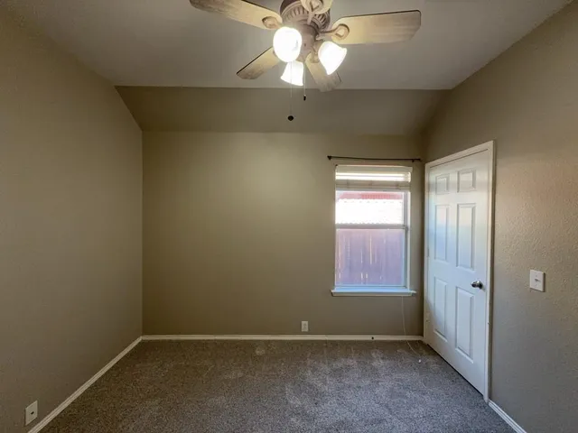 an empty room with a window and a fan