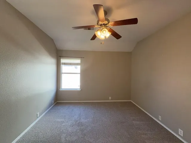 an empty room with a window and a fan