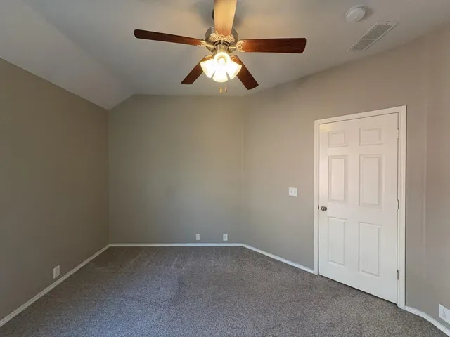 an empty room with a ceiling fan and a window