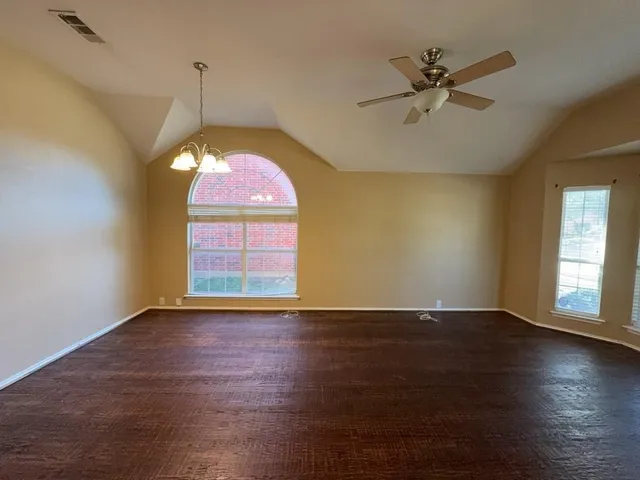 a view of an empty room with window and wooden floor