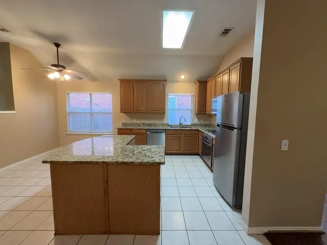 a kitchen with stainless steel appliances granite countertop a sink refrigerator and cabinets
