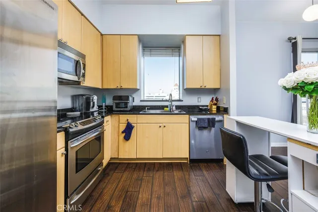 a kitchen with cabinets wooden floor and stainless steel appliances