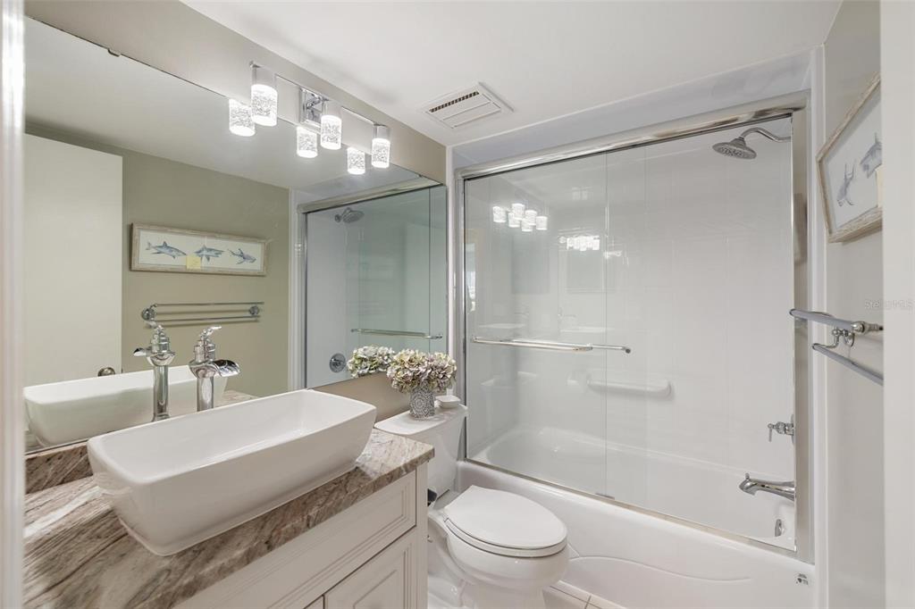 276 Cerromar Way South, Unit 60 Venice, FL 34293 - Photo 23 of 31 a bathroom with a sink a toilet a mirror and a glass door shower