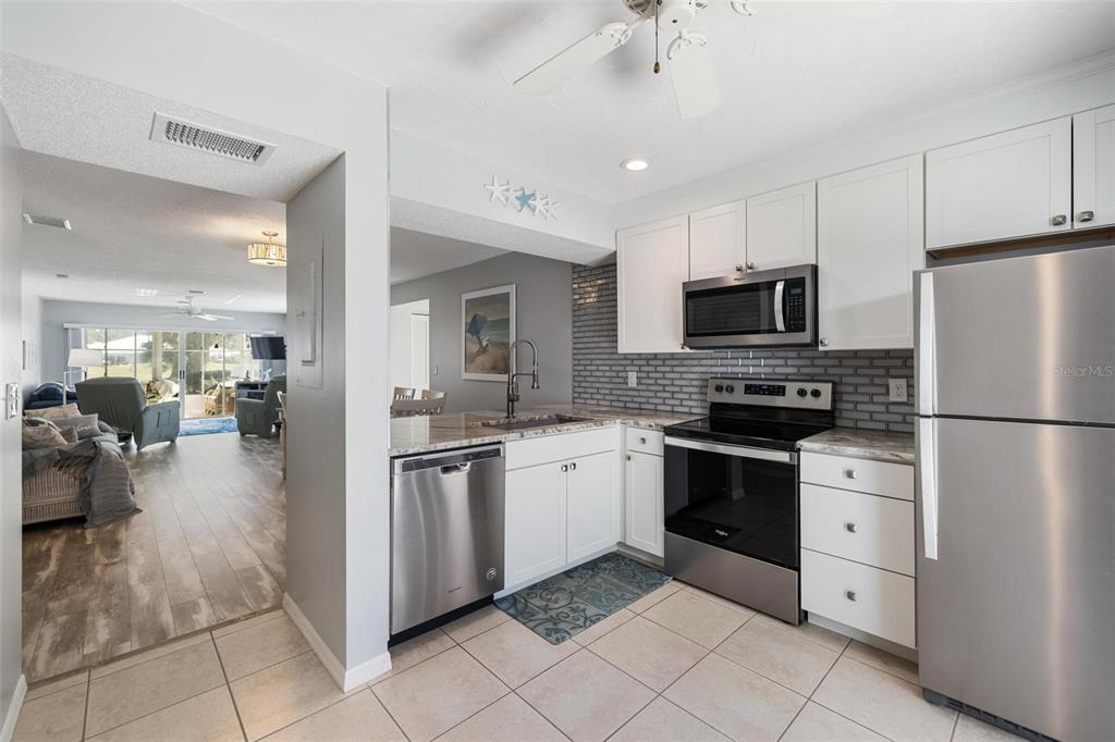 276 Cerromar Way South, Unit 60 Venice, FL 34293 - Photo 5 of 31 a kitchen with stainless steel appliances granite countertop a refrigerator a sink a stove top oven and cabinets