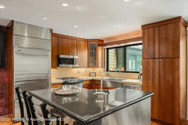 a kitchen with kitchen island granite countertop a sink a stove and a refrigerator
