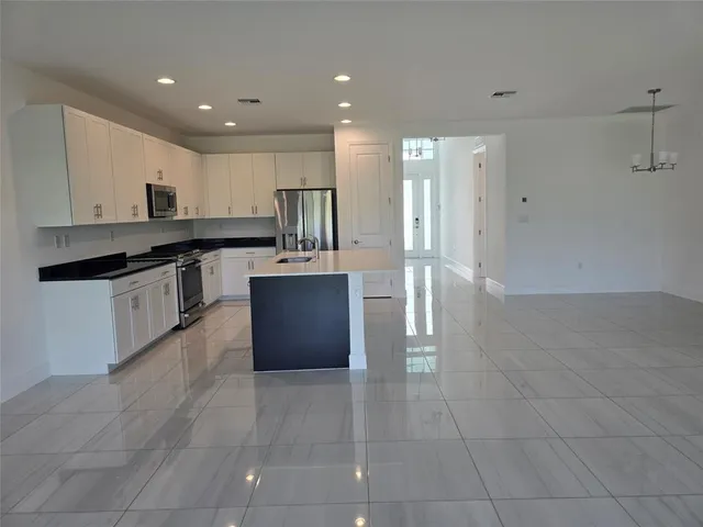 a large kitchen with stainless steel appliances granite countertop a large counter top and wooden floors