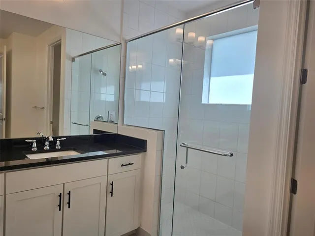 a bathroom with a granite countertop sink a mirror and a shower