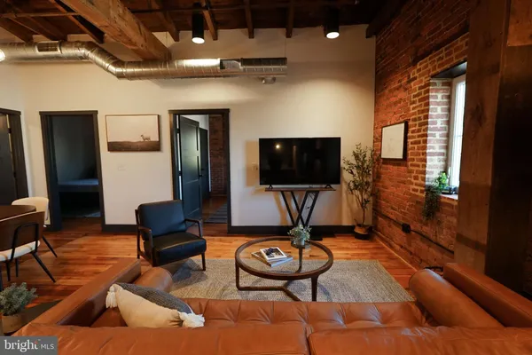 a living room with furniture a flat screen tv and floor to ceiling window