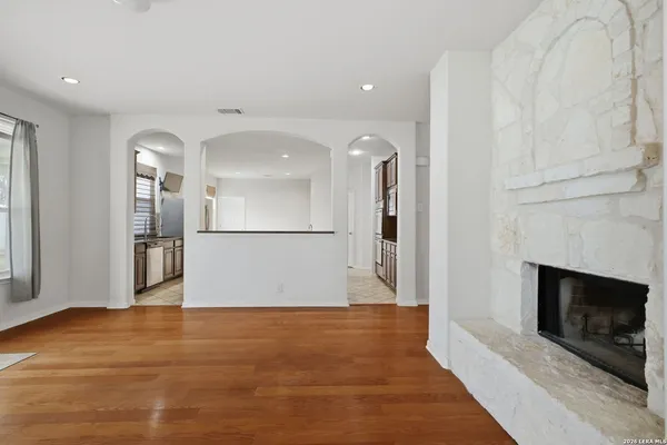 a view of a livingroom with wooden floor and a kitchen