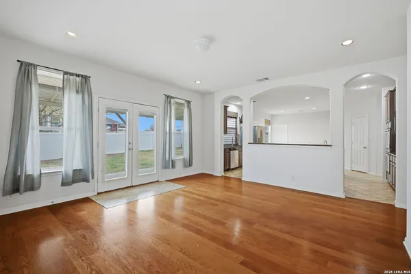 a view of an empty room with wooden floor and a kitchen
