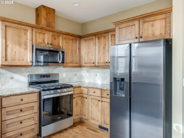 a kitchen with granite countertop a sink cabinets stainless steel appliances and a window