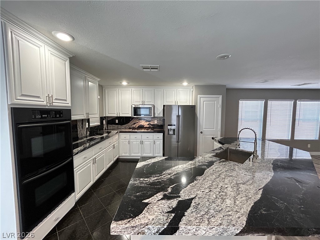 6538 Elm Spring Las Vegas, NV 89148 - Photo 4 of 29 Elegant kitchen boasts sleek black and white granite countertops and modern appliances.