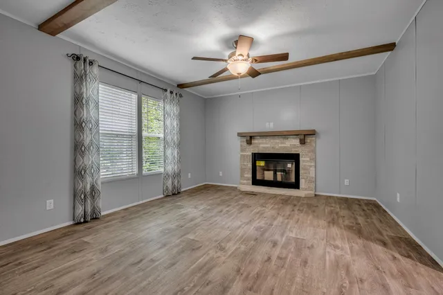 a view of an empty room with wooden floor fireplace and a window