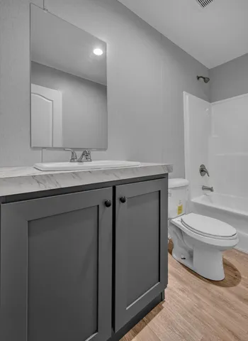 a bathroom with a granite countertop toilet a sink and a mirror