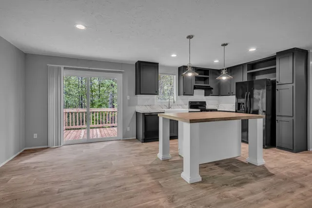 a kitchen with stainless steel appliances kitchen island granite countertop a refrigerator oven a sink with dishwasher and white cabinets