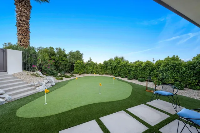 a view of swimming pool with a yard and palm trees