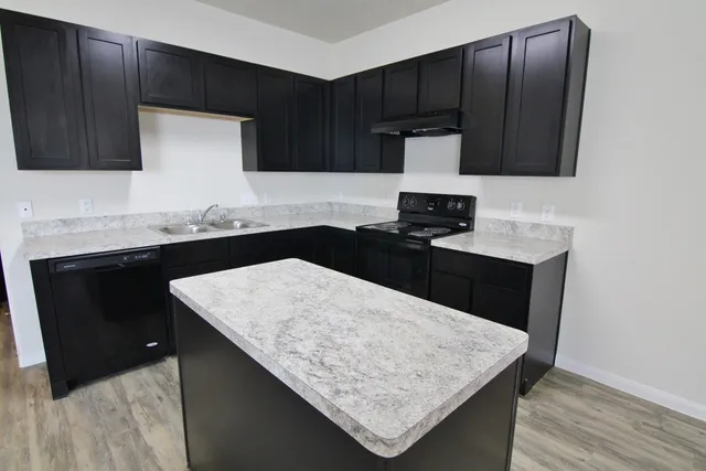 a kitchen with granite countertop wooden cabinets and black appliances