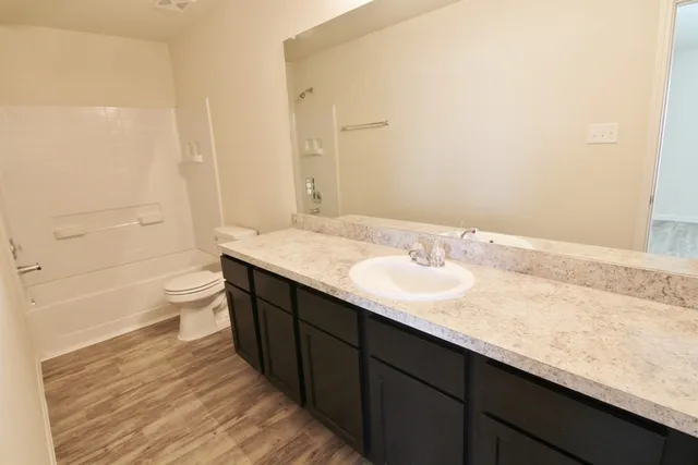 a bathroom with a granite countertop sink a toilet and shower