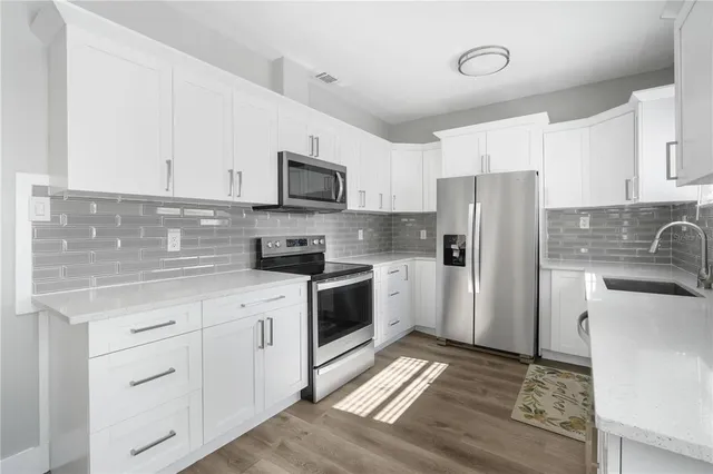 a kitchen with white cabinets and stainless steel appliances