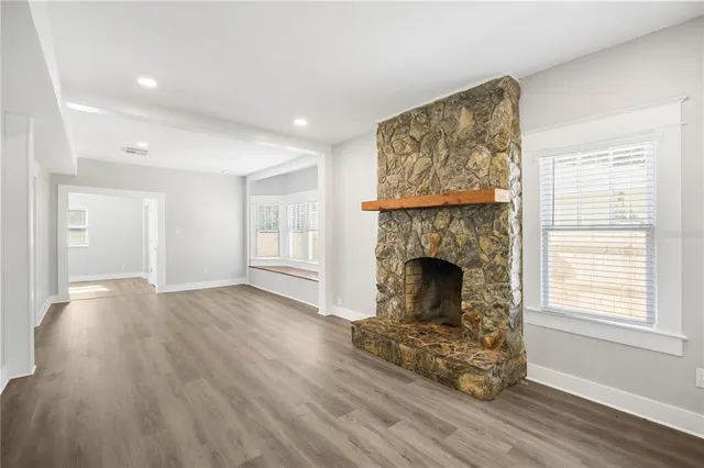 a view of a livingroom with wooden floor a fireplace and windows