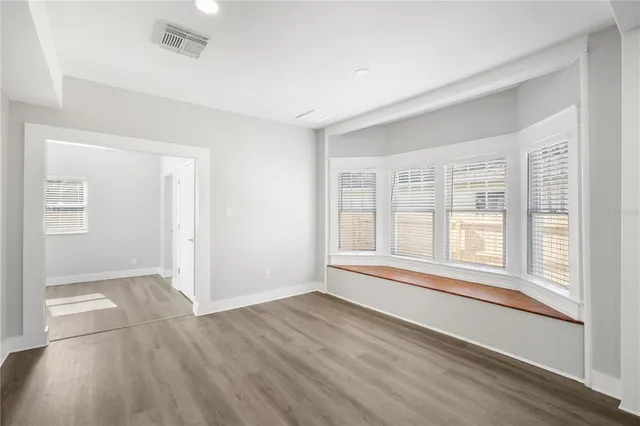 an empty room with wooden floor and windows