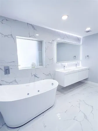 a bathroom with a bathtub a mirror a sink and vanity