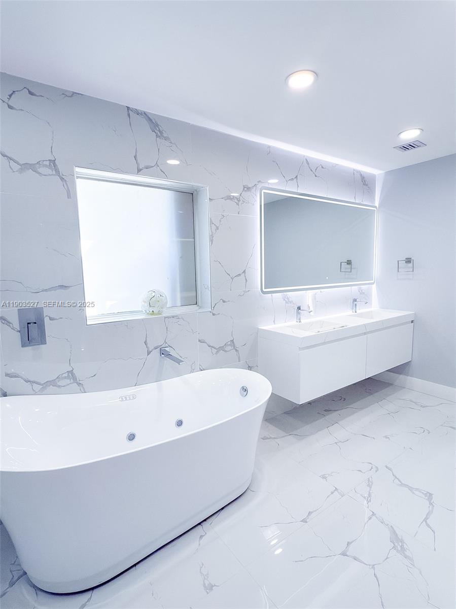 19245 Southwest 188th Street Miami, FL 33187 - Photo 24 of 38 a bathroom with a bathtub a mirror a sink and vanity