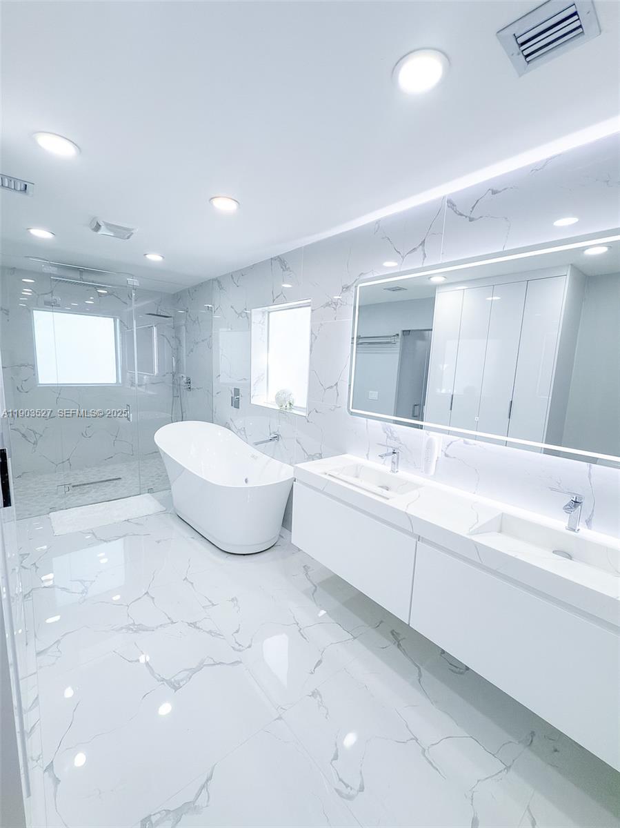 19245 Southwest 188th Street Miami, FL 33187 - Photo 25 of 38 a spacious bathroom with a double vanity sink a mirror and a bathtub