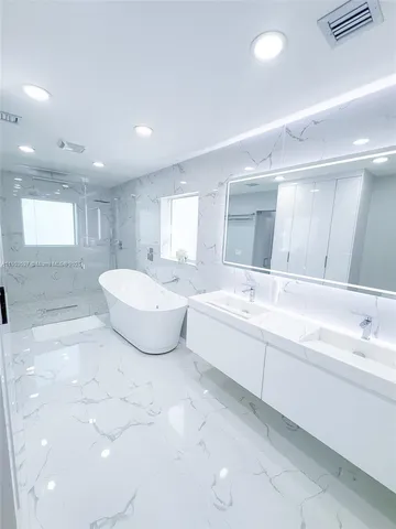 a spacious bathroom with a double vanity sink a mirror and a bathtub