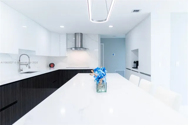 a kitchen with stainless steel appliances a sink a stove a refrigerator a sink a dining table and chairs