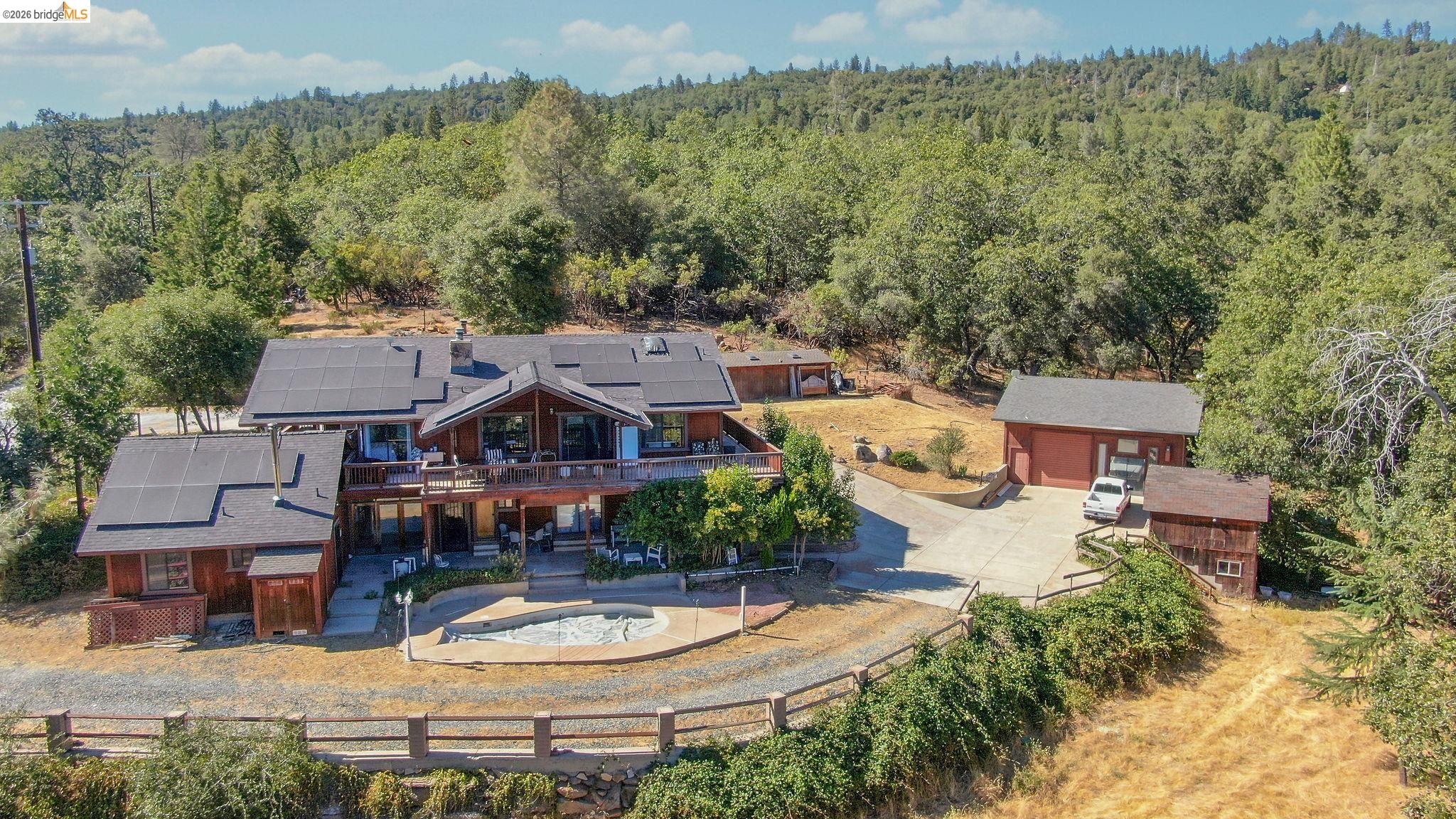 22963 Robertson Ranch Road Sonora, CA 95370 - Photo 77 of 90 Spacious property featuring a main residence with multiple solar panels, an exterior deck, and an in-ground swimming pool