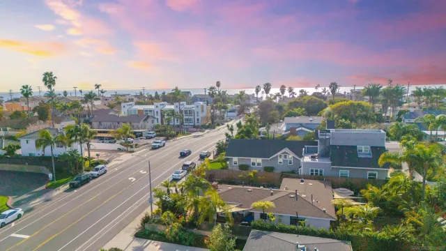 an aerial view of a city with lots of residential buildings ocean and mountain view in back