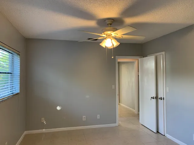 an empty room with a window and a ceiling fan