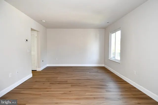 a view of an empty room with wooden floor and window
