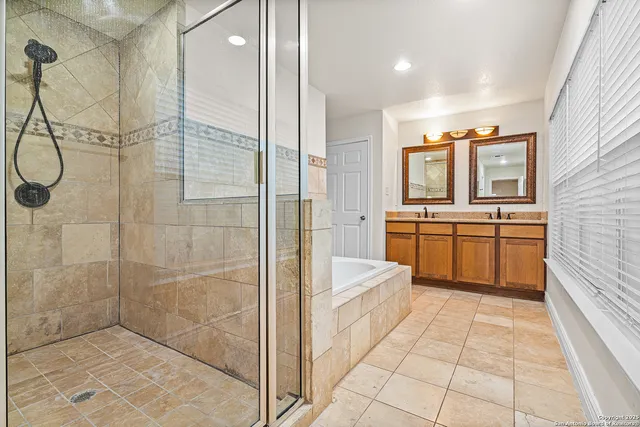 a bathroom with a tub a sink a mirror and a shower