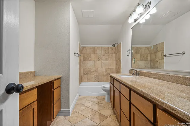 a bathroom with a granite countertop sink a toilet a mirror and bathtub