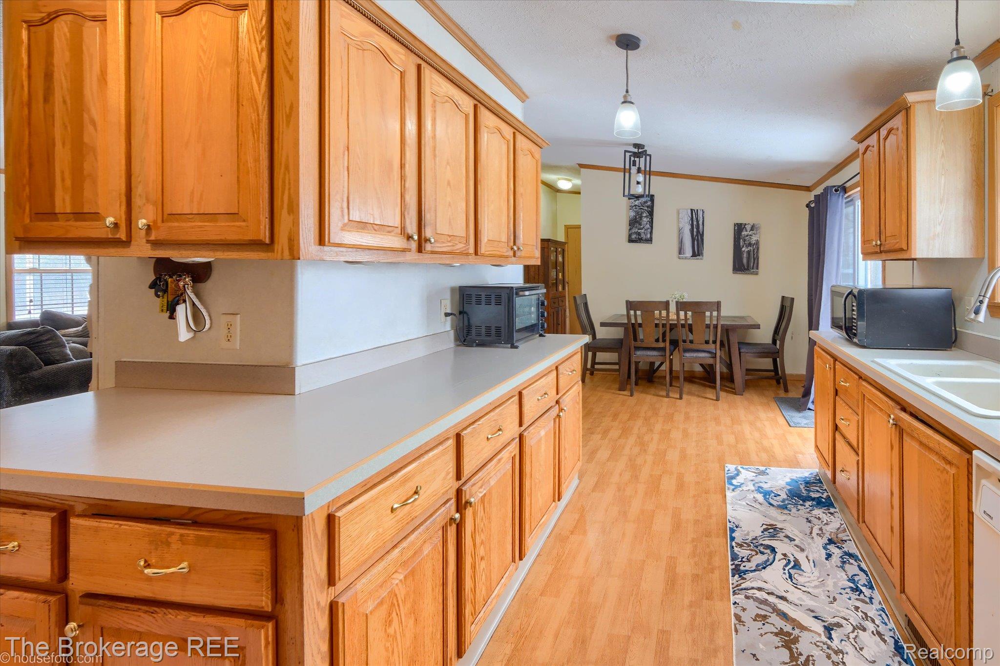 8247 North Center Road Mount Morris, MI 48458 - Photo 22 of 46 Kitchen featuring light countertops, ornamental molding, pendant lighting, black microwave, and light wood-type flooring