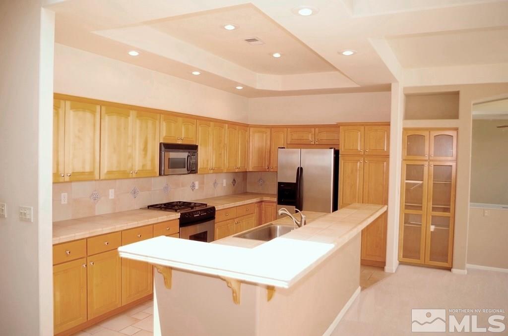 3327 Skyline Boulevard Reno, NV 89509 - Photo 11 of 17 a kitchen with stainless steel appliances a stove refrigerator sink and cabinets