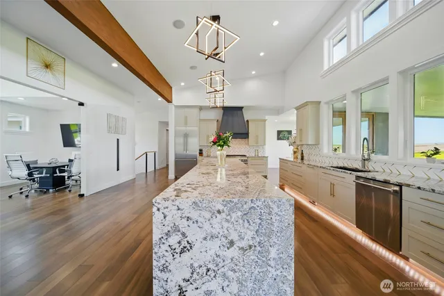 a large kitchen with kitchen island a stove a sink dishwasher a dining table and chairs with wooden floor