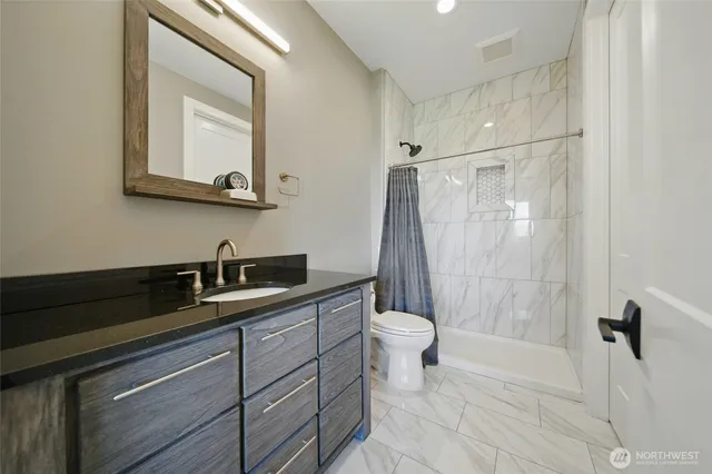 a bathroom with a granite countertop sink a toilet and a mirror