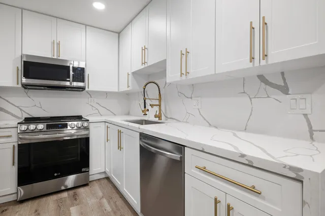 a kitchen with stainless steel appliances granite countertop a sink a stove a microwave and cabinets